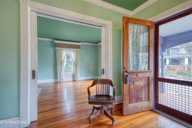 living area featuring crown molding and light hardwood / wood-style flooring