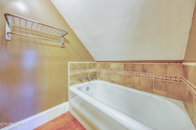 bathroom with lofted ceiling and a bathing tub