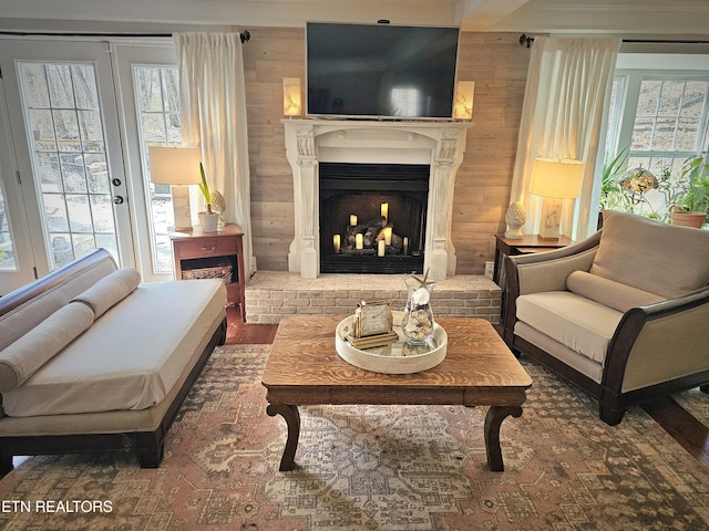 sitting room with wood-type flooring, a brick fireplace, and wood walls