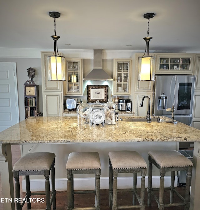 kitchen featuring wall chimney exhaust hood, stainless steel fridge, and cream cabinets