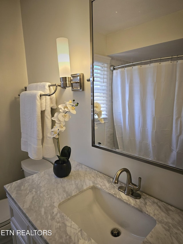 bathroom with walk in shower, vanity, and toilet