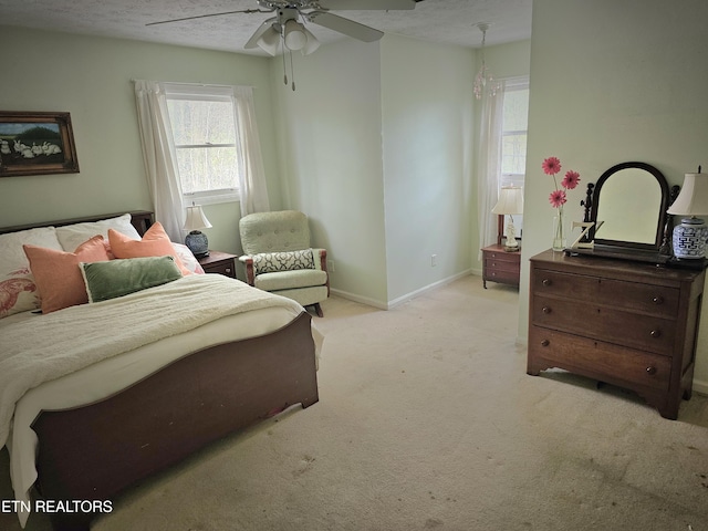 bedroom with a textured ceiling, light colored carpet, and ceiling fan