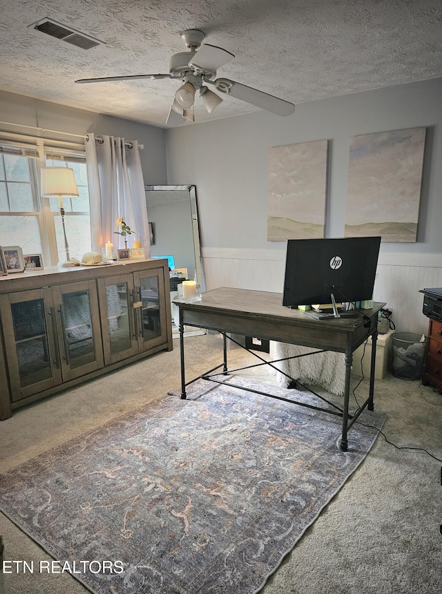 home office with carpet flooring, ceiling fan, and a textured ceiling