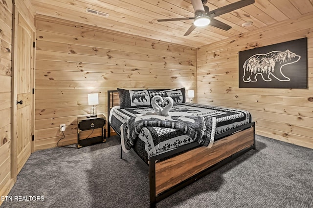 bedroom with ceiling fan, wooden walls, wooden ceiling, and dark carpet