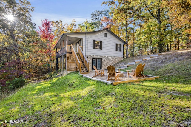 back of house featuring a fire pit, a deck, and a lawn