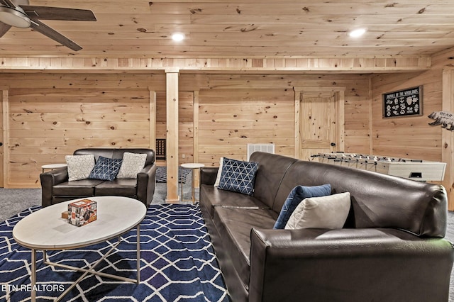 living room featuring dark colored carpet, ceiling fan, wooden ceiling, and wood walls