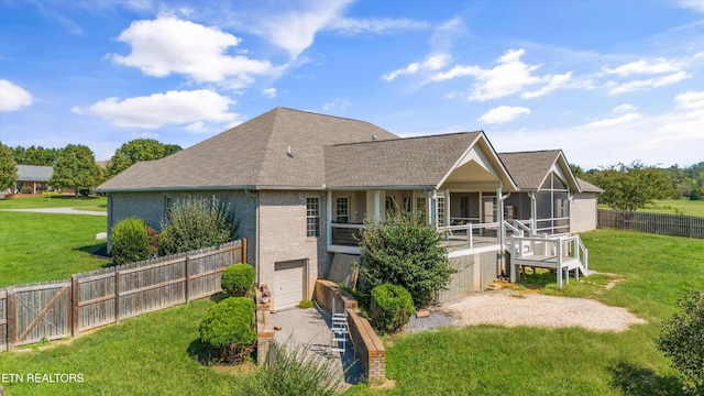 view of front of home featuring a front yard, a garage, and a sunroom