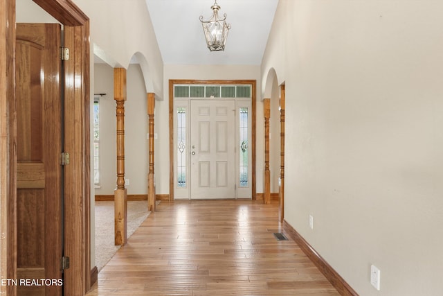 foyer featuring light hardwood / wood-style floors, lofted ceiling, and an inviting chandelier