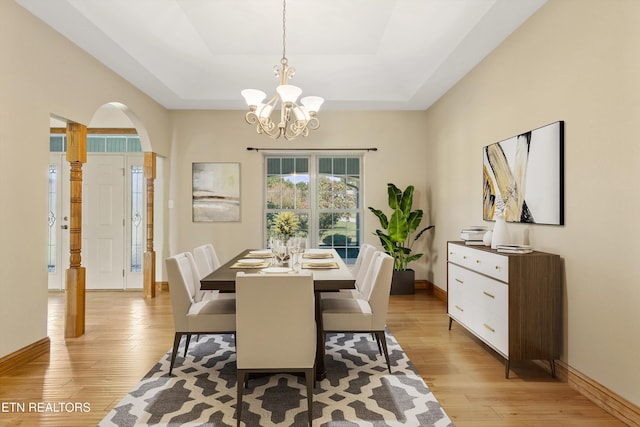 dining room featuring light hardwood / wood-style floors, a tray ceiling, and a notable chandelier