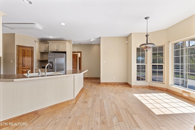 kitchen featuring pendant lighting, plenty of natural light, stainless steel fridge with ice dispenser, and sink