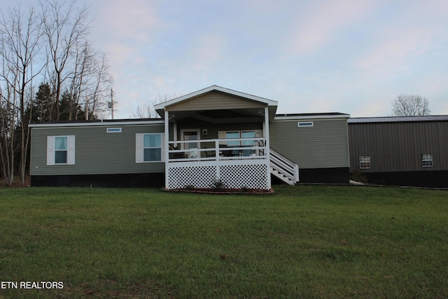 back of house featuring covered porch and a yard