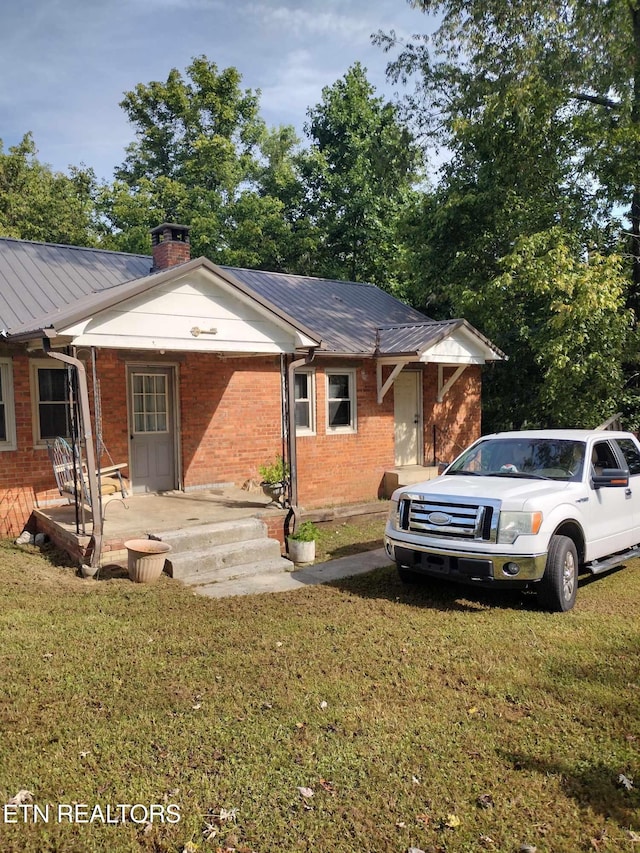 1331 Greenlee Ln, Jellico, TN 37762 - view of front of home with a chimney, brick siding, a front lawn, and metal roof