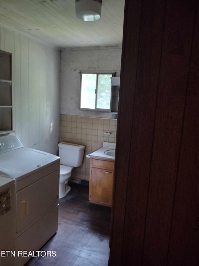 bathroom featuring vanity, wood-type flooring, toilet, and washing machine and clothes dryer