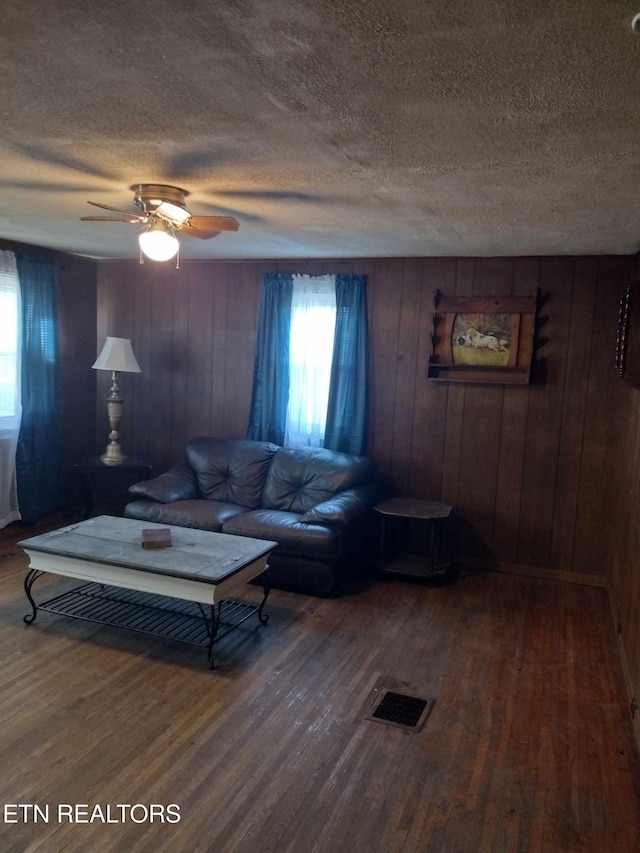 living room featuring hardwood / wood-style flooring, ceiling fan, and a textured ceiling