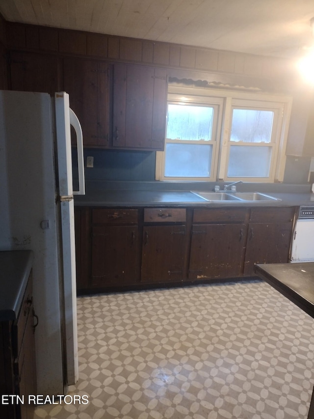 kitchen featuring white refrigerator, dark brown cabinets, and sink