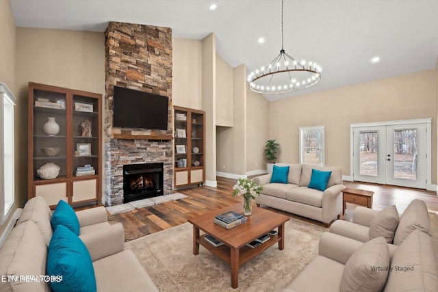 living room with light hardwood / wood-style floors, a fireplace, high vaulted ceiling, and french doors