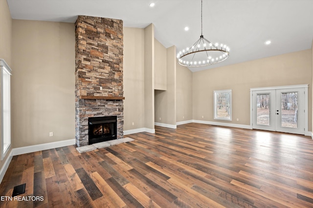 unfurnished living room featuring a stone fireplace, french doors, high vaulted ceiling, and wood-type flooring