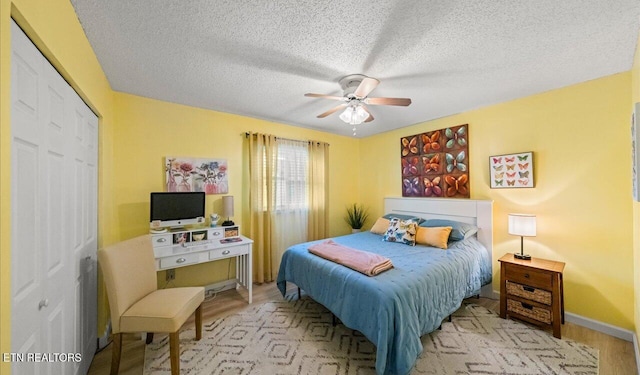 bedroom featuring a textured ceiling, a closet, light hardwood / wood-style flooring, and ceiling fan