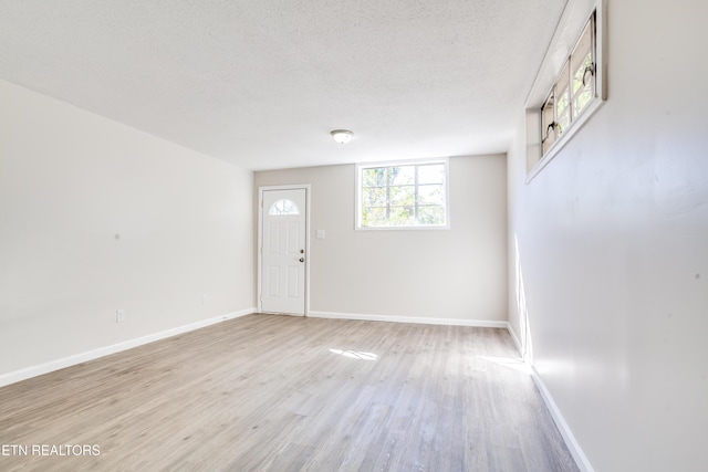 unfurnished room with light hardwood / wood-style floors and a textured ceiling