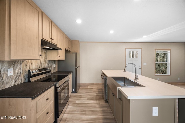 kitchen featuring light brown cabinets, sink, an island with sink, appliances with stainless steel finishes, and light hardwood / wood-style floors