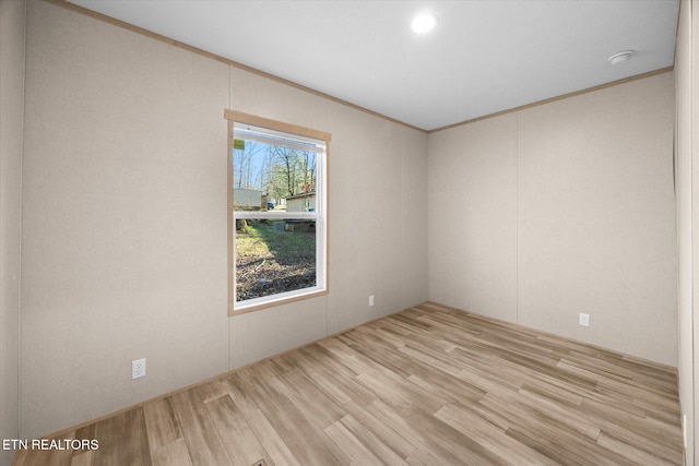 spare room with light wood-type flooring and crown molding