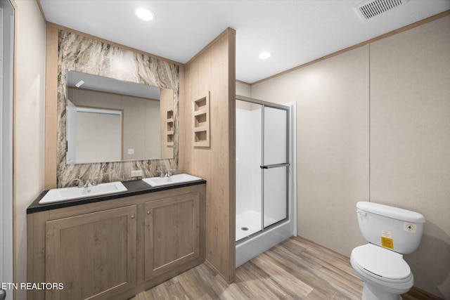 bathroom with vanity, a shower with door, hardwood / wood-style flooring, toilet, and ornamental molding