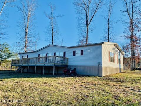 rear view of house with a deck and a lawn