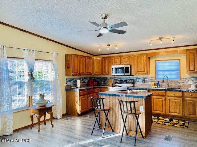 kitchen with a breakfast bar, a center island, backsplash, hardwood / wood-style flooring, and appliances with stainless steel finishes