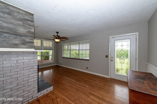 unfurnished living room with ceiling fan, dark wood-type flooring, and a textured ceiling