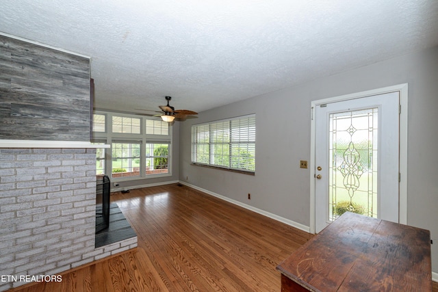 unfurnished living room featuring plenty of natural light, a textured ceiling, ceiling fan, and dark hardwood / wood-style floors