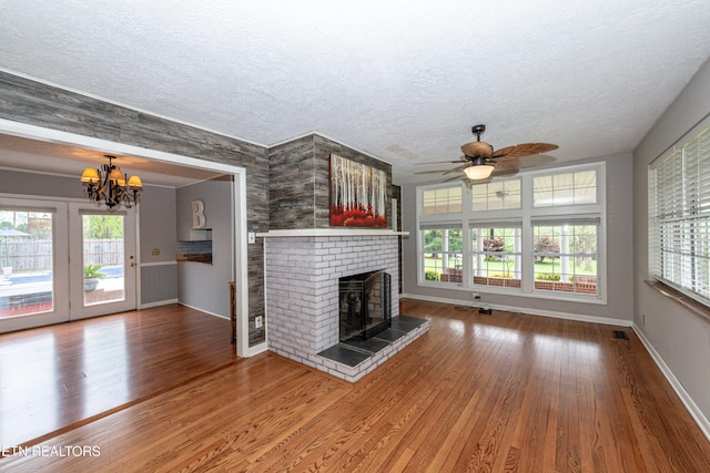 unfurnished living room featuring a textured ceiling, ceiling fan with notable chandelier, and wood-type flooring