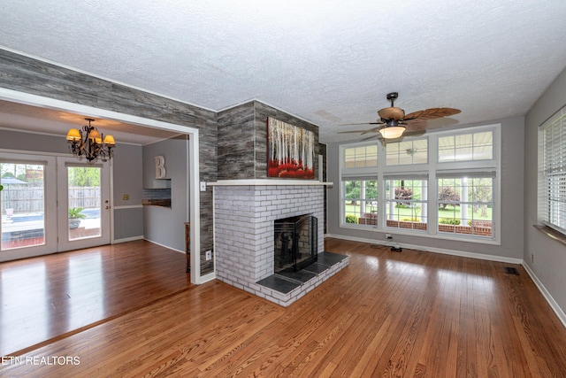 unfurnished living room with ceiling fan with notable chandelier, a textured ceiling, and wood-type flooring