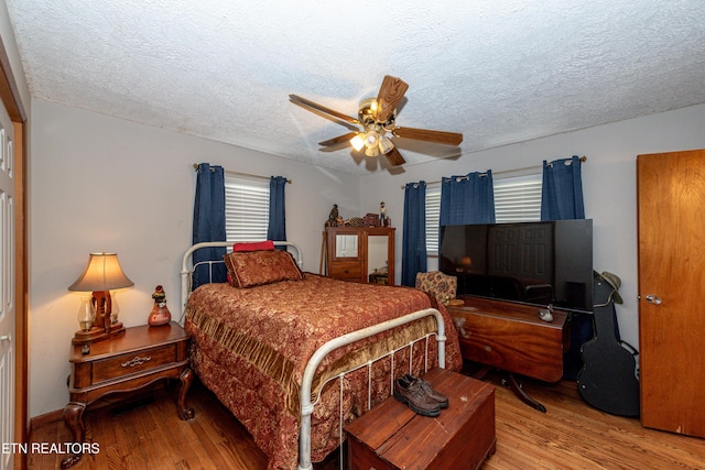 bedroom featuring hardwood / wood-style floors, a textured ceiling, and ceiling fan