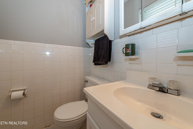 bathroom with tile walls, vanity, and toilet