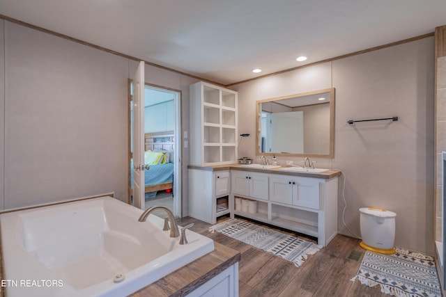 ensuite bathroom featuring wood finished floors, ensuite bath, double vanity, a sink, and a garden tub