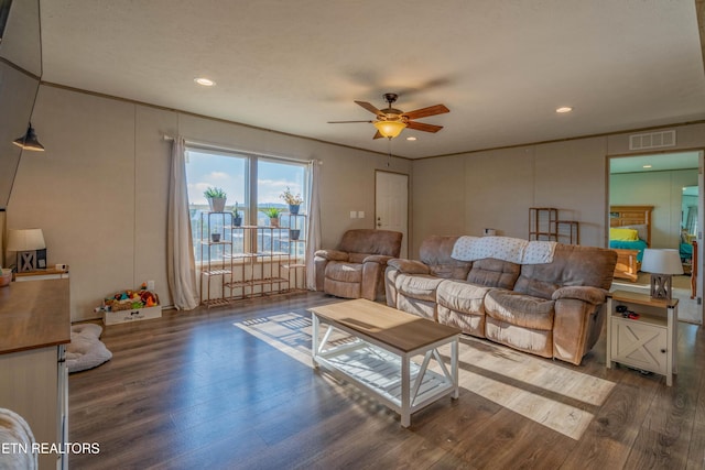 living room with a ceiling fan, crown molding, wood finished floors, and visible vents