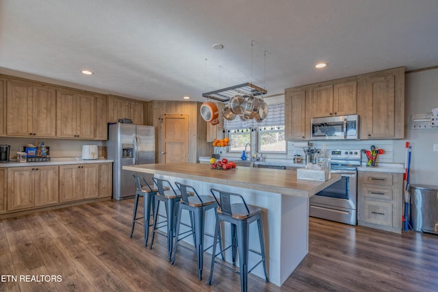 kitchen featuring a kitchen bar, a kitchen island, dark wood-style floors, recessed lighting, and appliances with stainless steel finishes