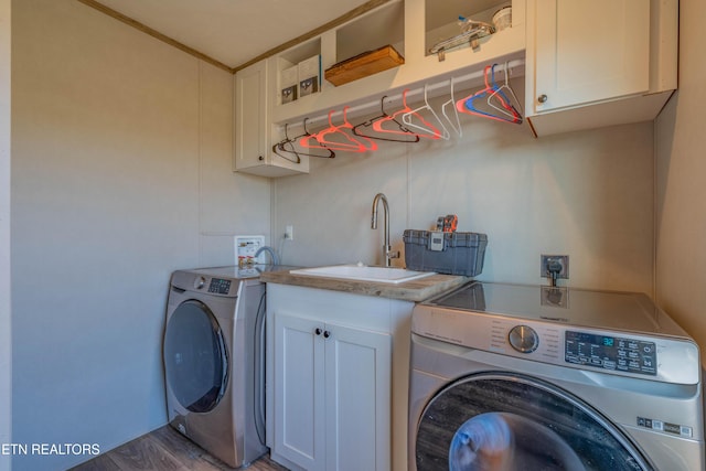 clothes washing area featuring washing machine and clothes dryer, cabinet space, and a sink