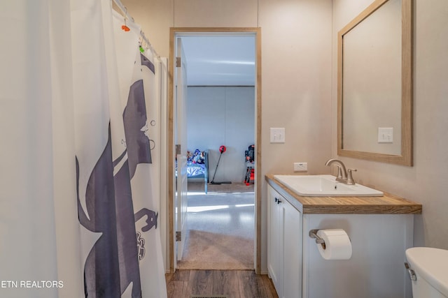 bathroom with toilet, vanity, and wood finished floors