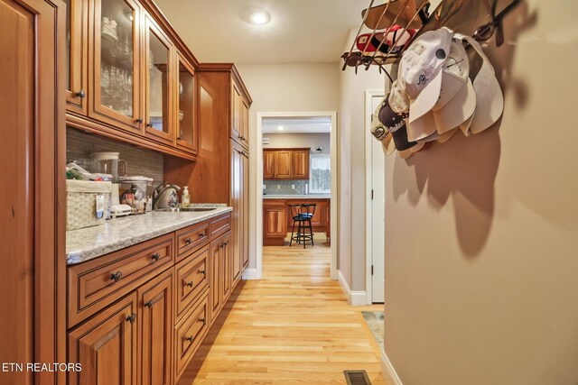 interior space featuring light stone countertops, light wood-type flooring, backsplash, and sink