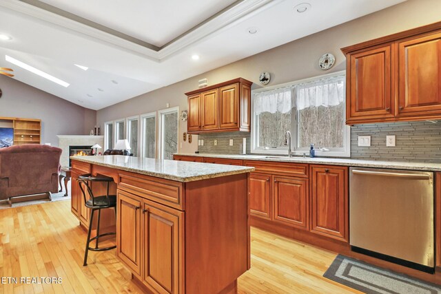 kitchen with dishwasher, a healthy amount of sunlight, backsplash, sink, and a kitchen island