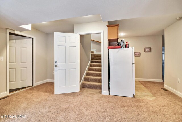 basement featuring white fridge and light colored carpet