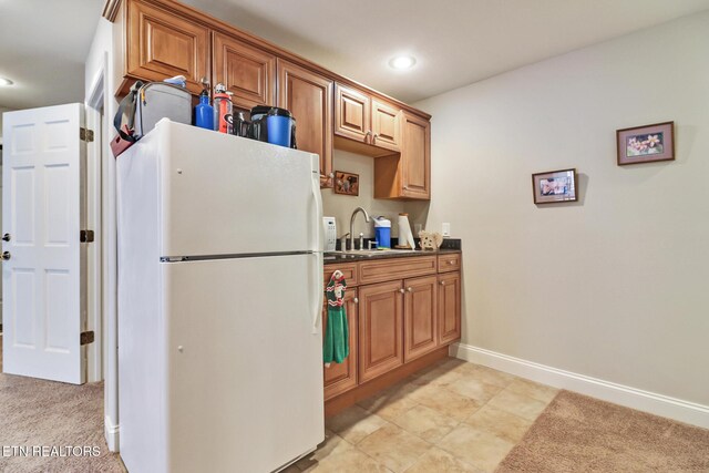 kitchen with light carpet, sink, and white fridge