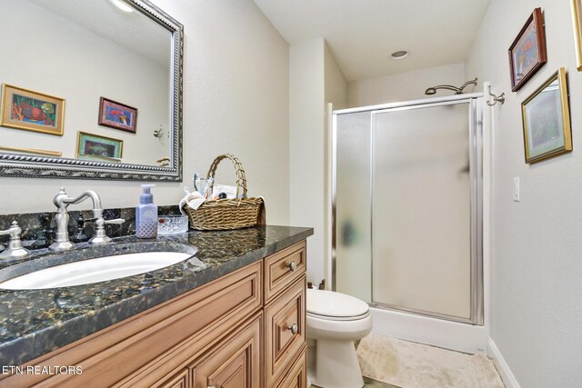 bathroom featuring tile patterned flooring, vanity, toilet, and a shower with door