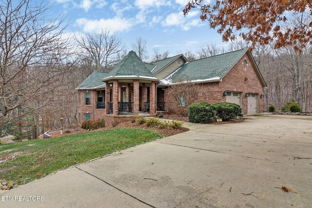 view of front of home with a garage, covered porch, and a front lawn