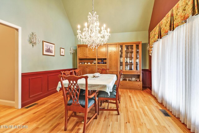 dining area featuring light wood-type flooring, high vaulted ceiling, and a chandelier