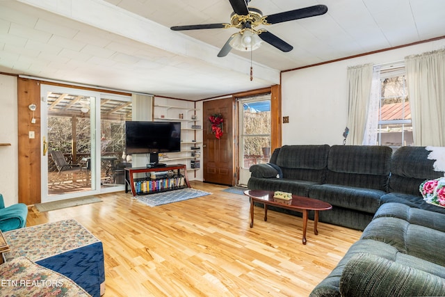 living room with hardwood / wood-style flooring, ceiling fan, built in features, and ornamental molding