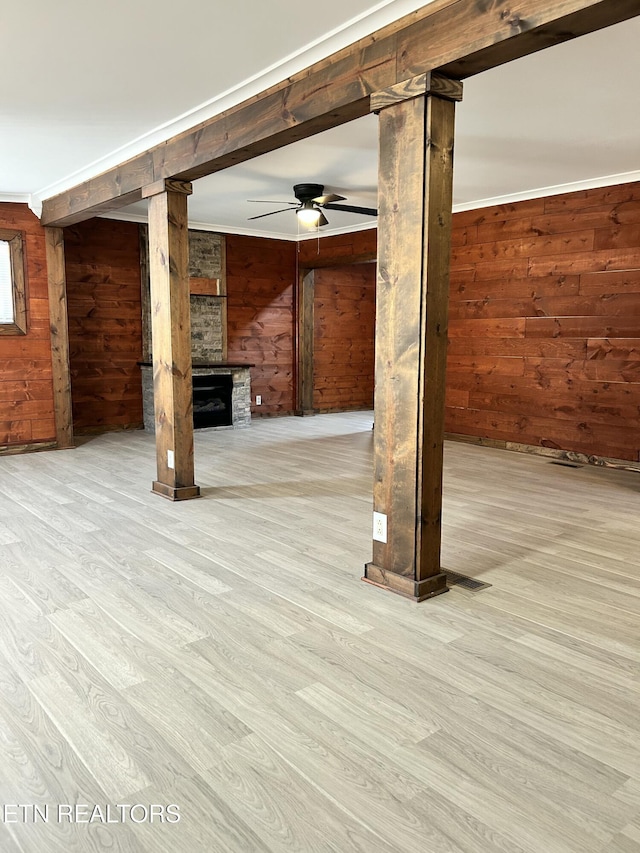 basement featuring light hardwood / wood-style flooring, crown molding, and wood walls