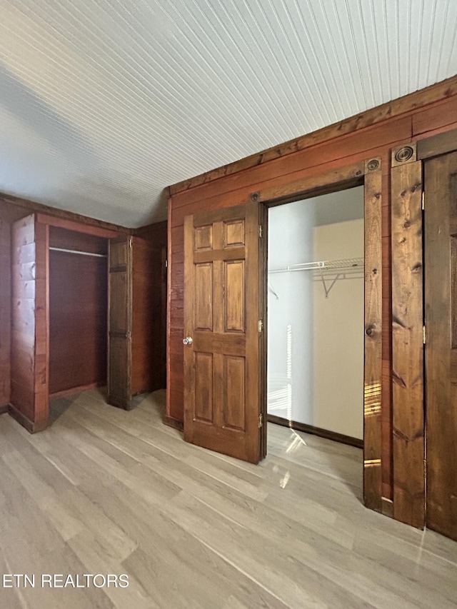 unfurnished bedroom featuring wooden walls and light hardwood / wood-style floors