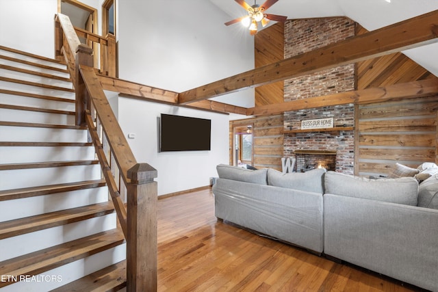 living room featuring a fireplace, light hardwood / wood-style floors, high vaulted ceiling, and ceiling fan